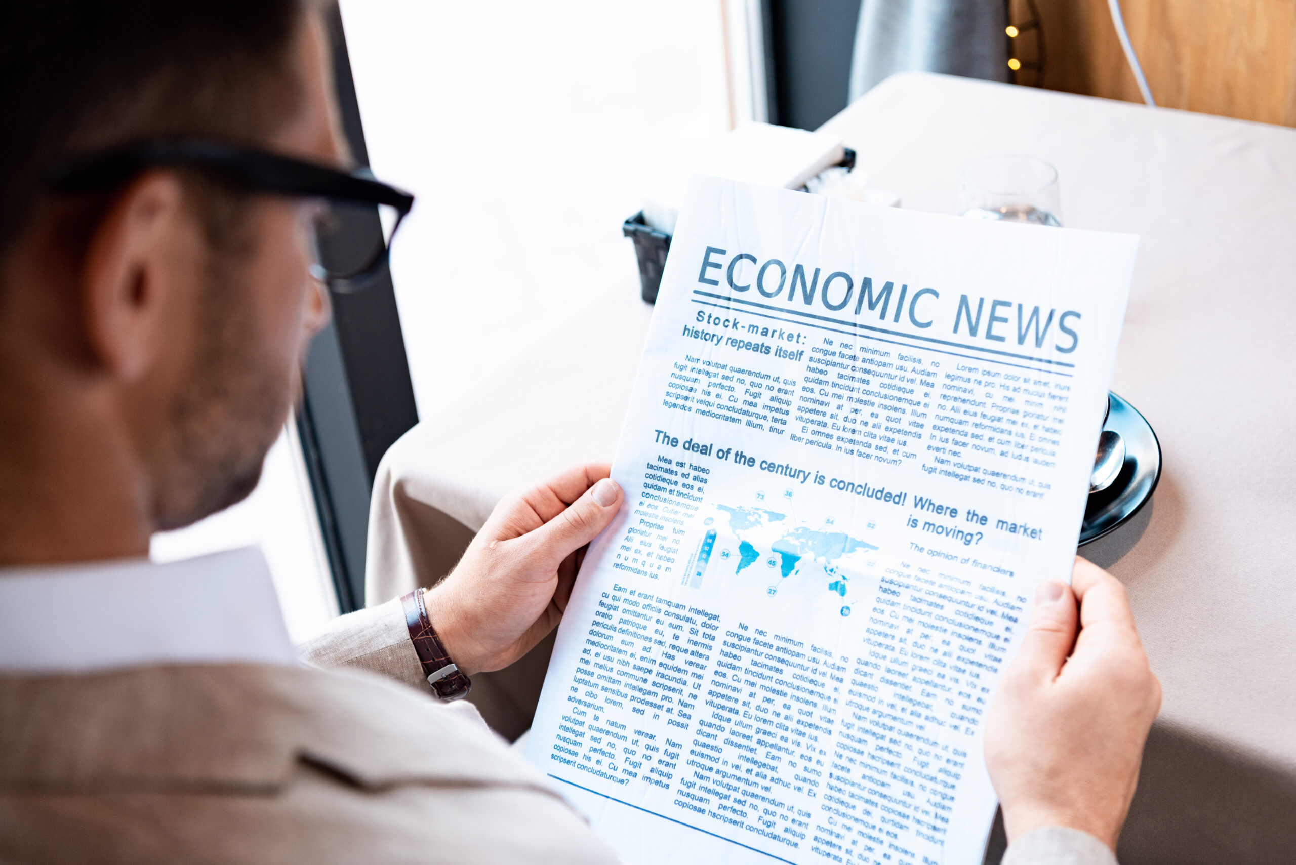 cropped view of businessman reading newspaper in cafe
